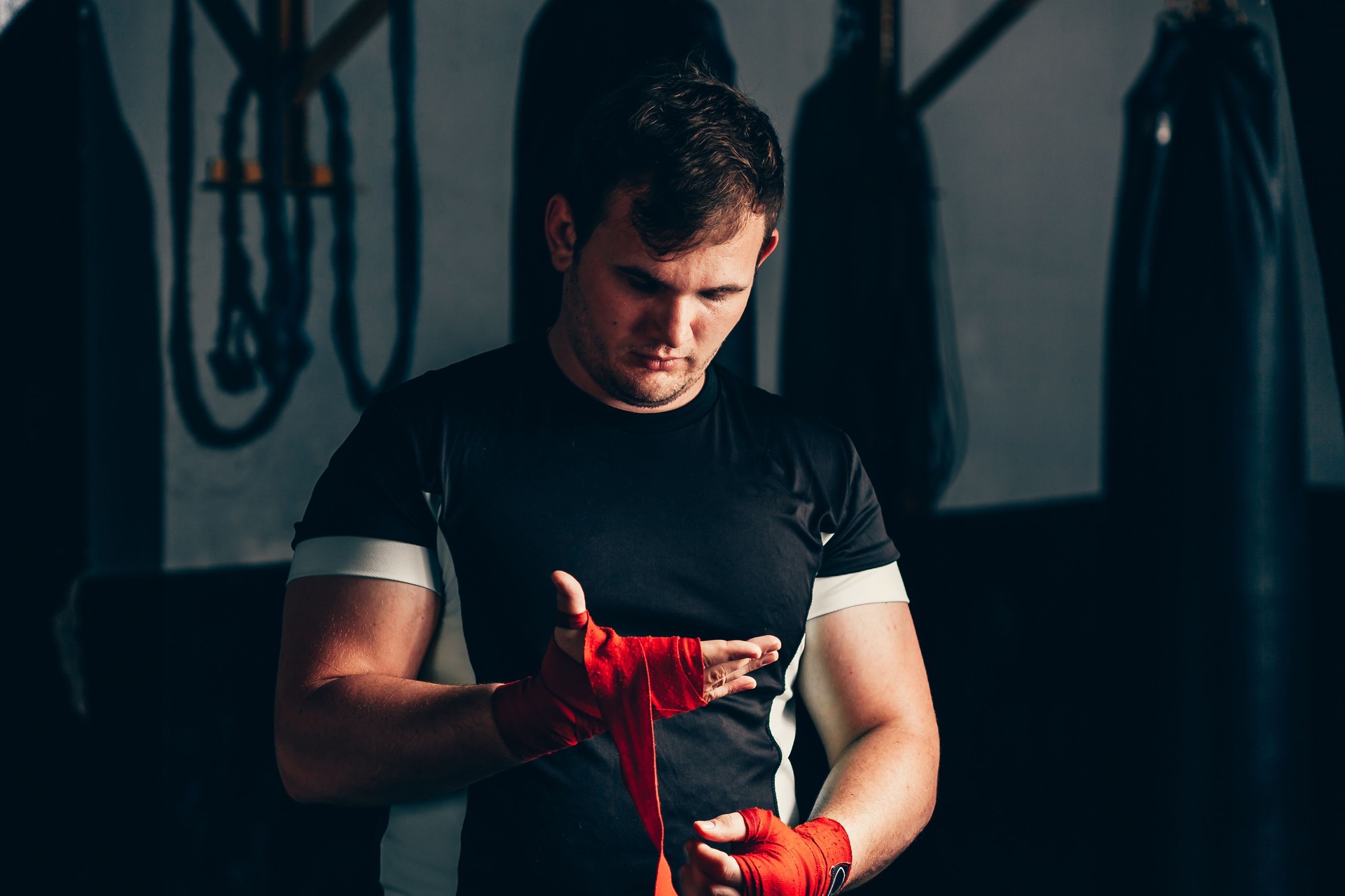 Strong boxer putting on red straps and getting ready to fight